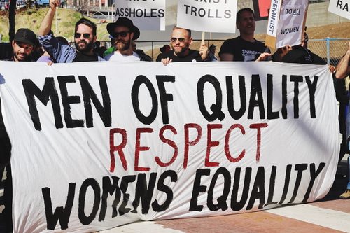 Männer tragen auf einer Demonstration ein Transparent mit dem Text "Men of Quality respect womens equality."