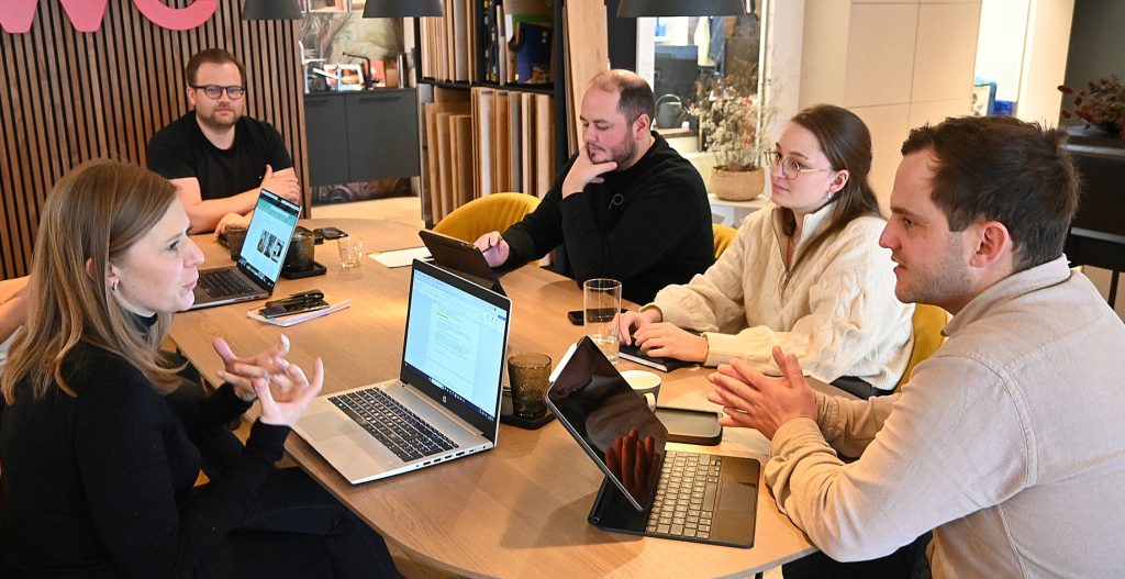 Menschen sitzen an einem Konferenztisch für Meeting mit SEO Textagentur